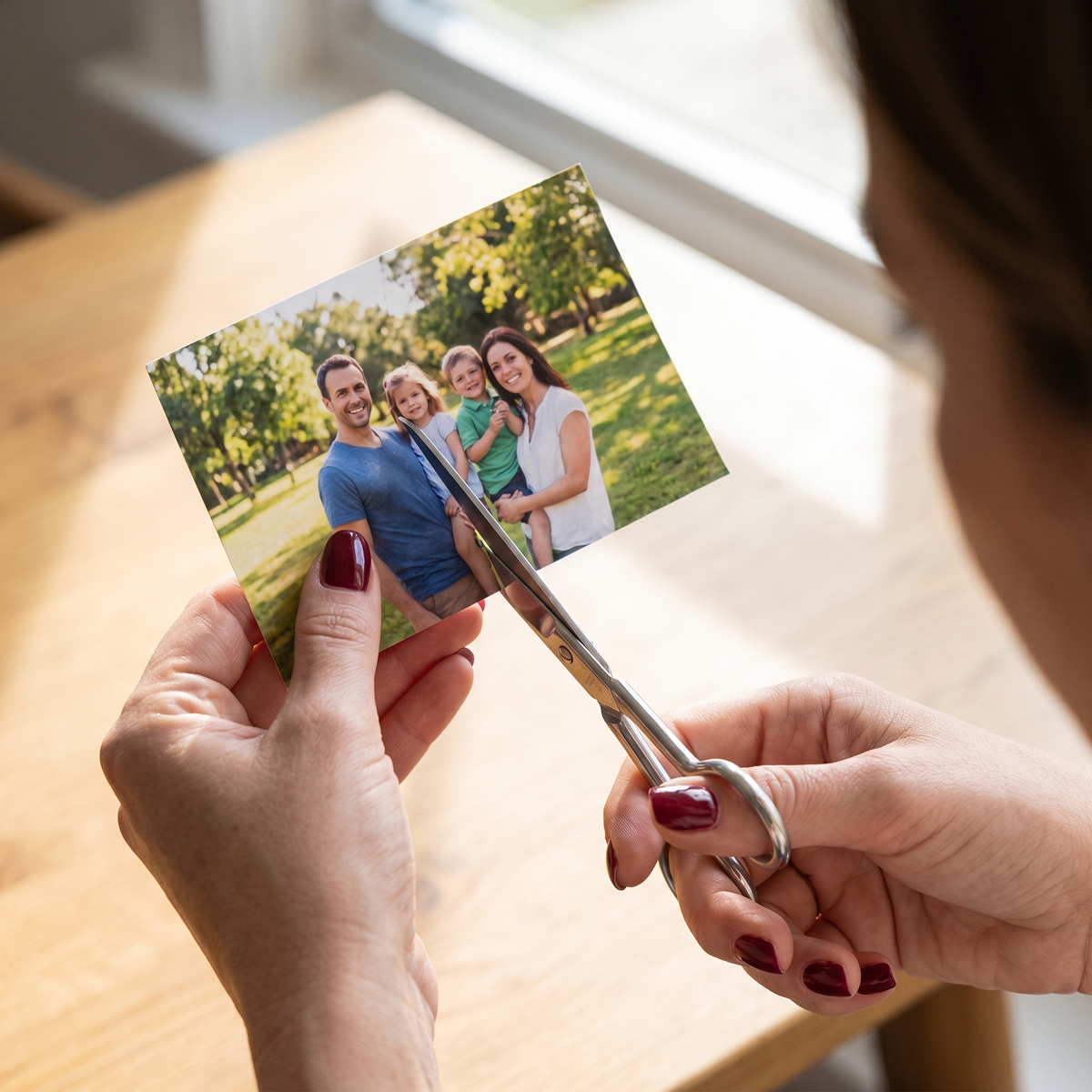 A woman cutting a man out of a family photo